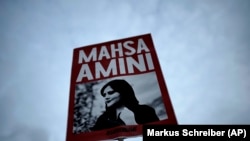 Жена държи плакат със снимка на Махса Амини по време на протест в Иран. 