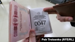 Гражданин России держит паспорт в здании миграционного центра обслуживания населения. Алматы, 3 октября 2022 года