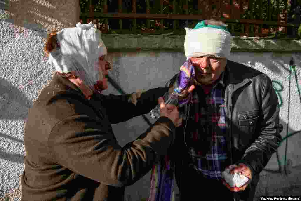 A woman helps a man after they were both injured during a Russian missile strike in Kyiv on October 10.