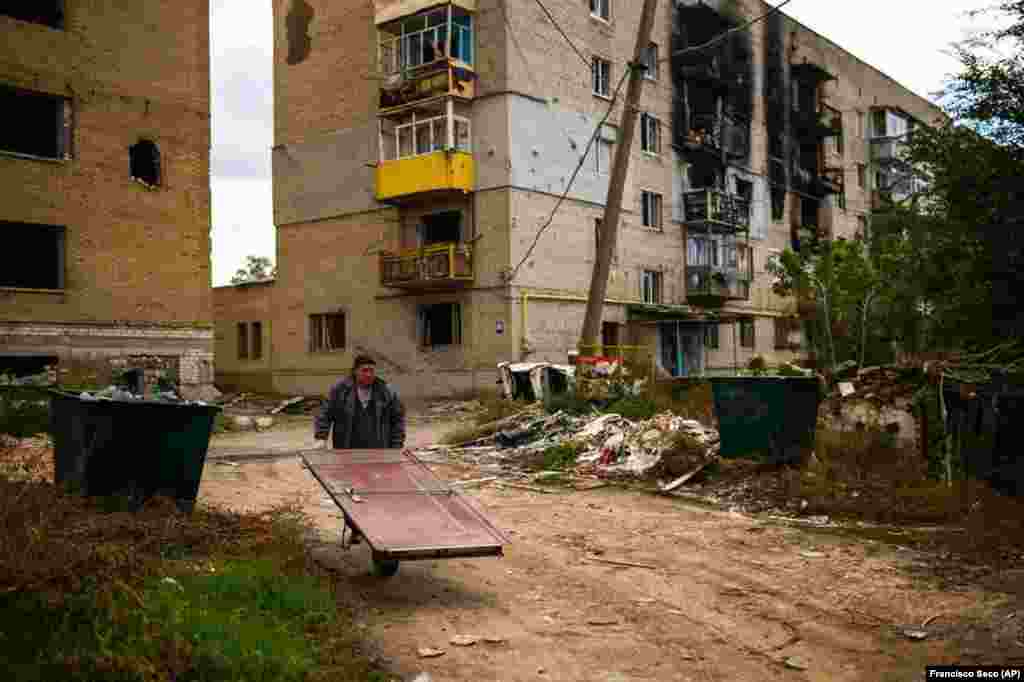 Many older residents have remained in their homes throughout the war, despite Ukrainian government pleas for them to move somewhere safer -- an option many in Izyum had only briefly in the spring before it was occupied. Mykola, 62, carries a door on a wheelbarrow to repair his home. Without electricity or gas, residents must prepare for the approaching winter.