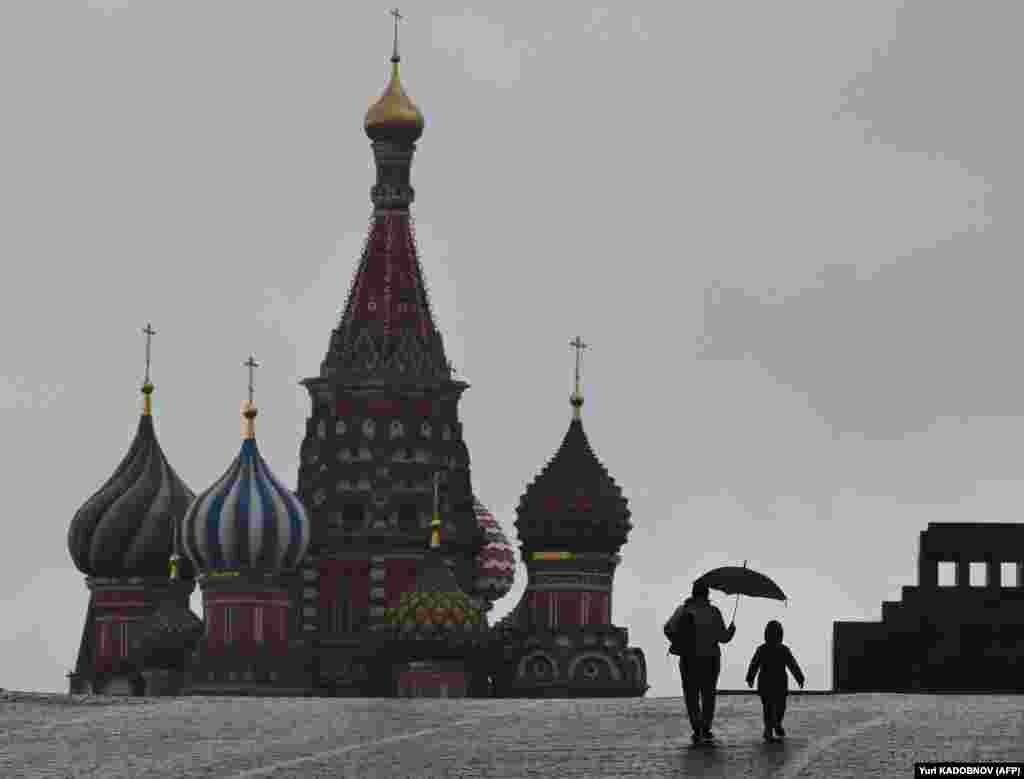 A woman and a child walk on Red Square in front of St. Basil&#39;s Cathedral in Moscow.