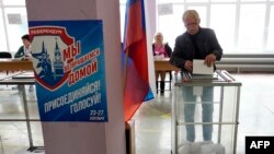 Мужчина голосует на так называемом референдуме о «присоединении» к России на избирательном участке в оккупированном Мариуполе, 23 сентября 2022 года
