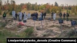 Officials inspect a mass grave discovered in the Donetsk region after liberation.