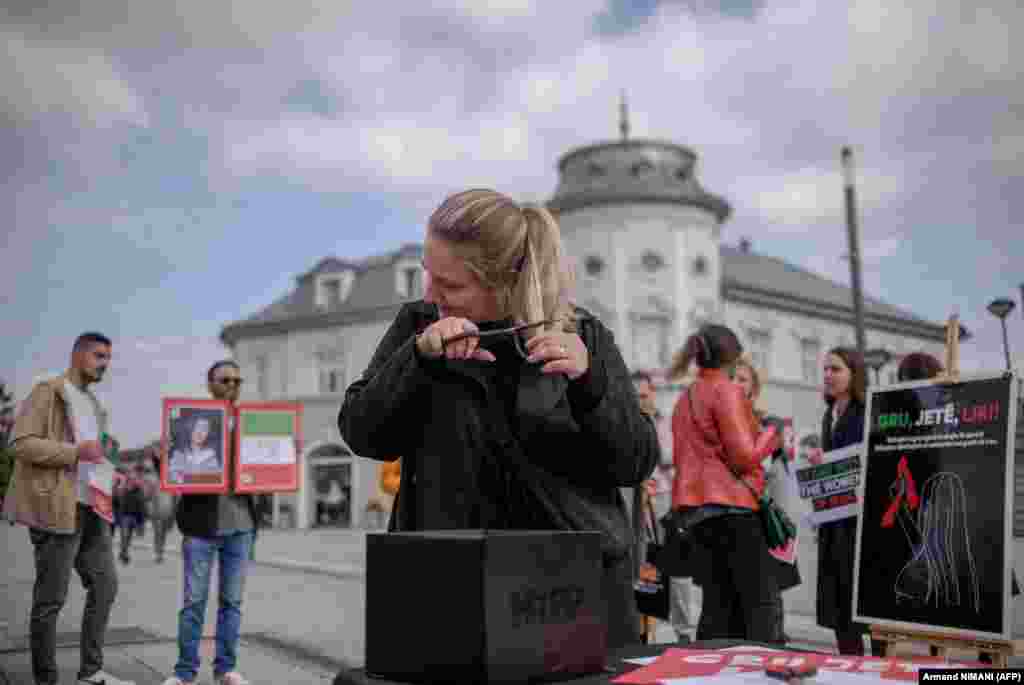 A woman cuts her hair during a rally in support of Iranian women in Pristina on October 12.