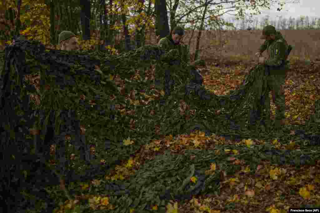 Ukrainian servicemen salvage a camouflage net from the Russian position near Hrakove. Such netting is highly valued by both sides in the current conflict for its ability to obscure vehicles and entrenched soldiers from drones.&nbsp;