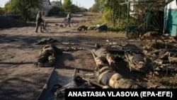 Local residents pass by the dead bodies of Russian soldiers on a street in the recaptured city of Lyman in the Luhansk area of Ukraine in October 2022.