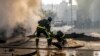 Egy tűzoltó segíti ki társát egy kráterből, miközben egy égő autót oltanak el a rakétatámadás után Kijevben 2022. október 10-én, hétfőn