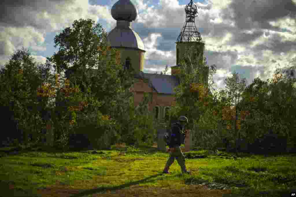 Украински войник минава покрай повредена от руска бомбардировка църква