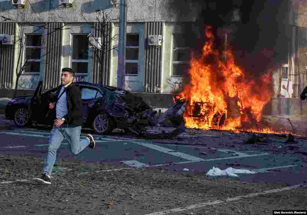 A man runs near a burning car that was struck by a Russian missile in central Kyiv. Russian President Vladimir Putin said the attacks were reprisals for Kyiv&#39;s &quot;terrorist&quot; actions, including an attack last weekend on a key bridge between Russia and the annexed Crimean Peninsula.