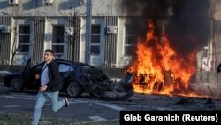 Мъж бяга от горяща кола на улица в Киев вследствие на руски удари, 10 октомври.