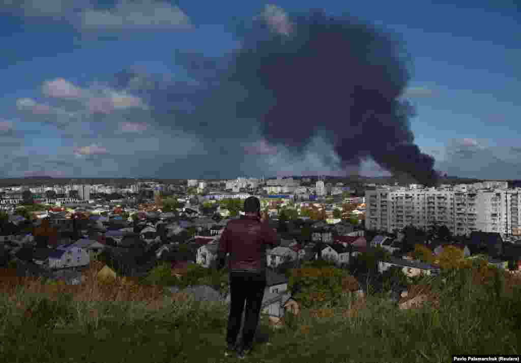 A man looks on as smoke rises over the western city of Lviv after it was hit by a Russian missile strike.&nbsp; Russia&rsquo;s attacks killed at least 11 people nationwide and wounded 64 others, the Ukrainian State Emergency Service said.