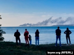 Жители Керчи следят за пожаром после взрыва на Керченском мосту. 8 октября 2022 года
