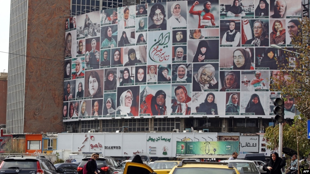 Iranians drive past a huge billboard showing a montage of pictures featuring Iranian women wearing the hijab in Tehran on October 13.