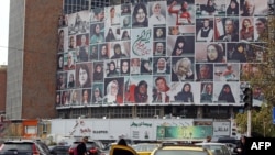 Iranians drive past a huge billboard showing a montage of pictures featuring Iranian women wearing the hijab in Tehran on October 13.