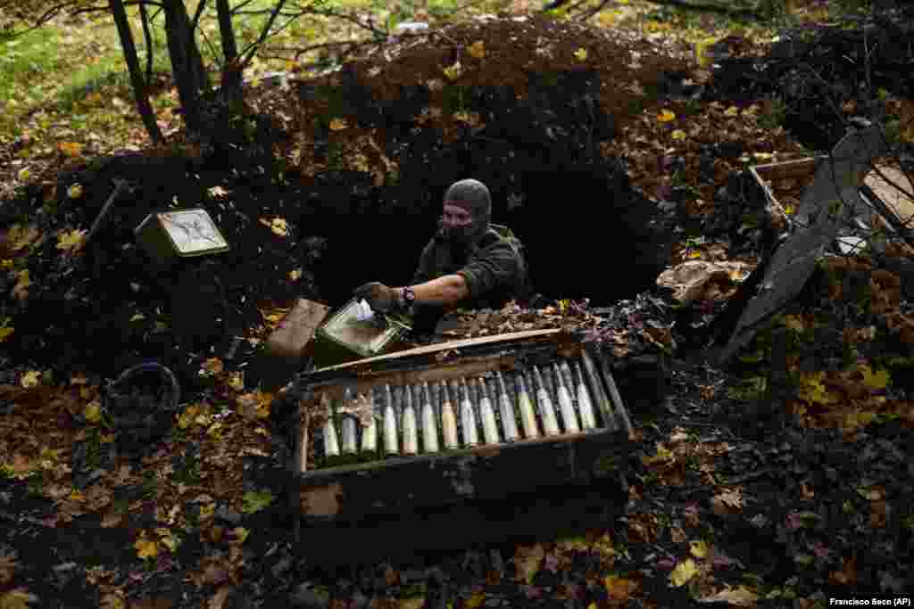 A Ukrainian deminer opens an ammunition case at a foxhole in the abandoned Russian position.&nbsp;