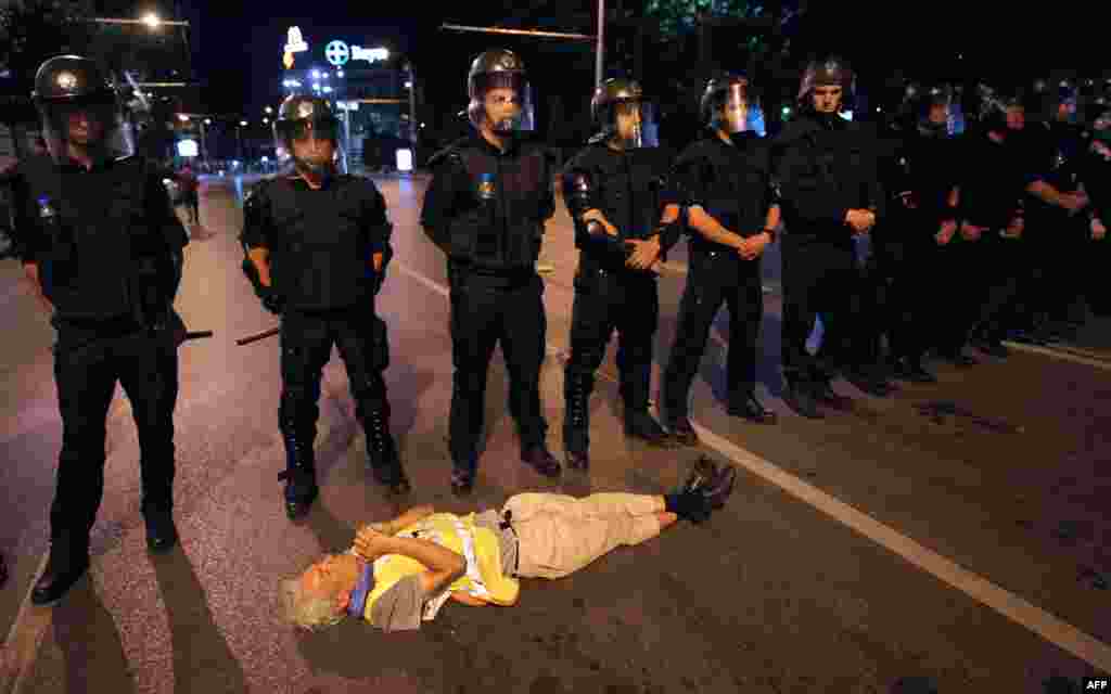 A protester lies in front of Bulgarian riot police who are making way for lawmakers to exit parliament during an antigovernment protest in Sofia. (AFP/Nikolay Doychinov)