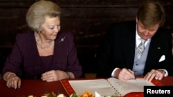 Нидерланды - Наследный принц Виллем-Александр (справа) подписывает акт отречения его матери королевы Беатрикс во время церемонии в Королевском Дворце в Амстердаме, 30 апреля 2013 г.