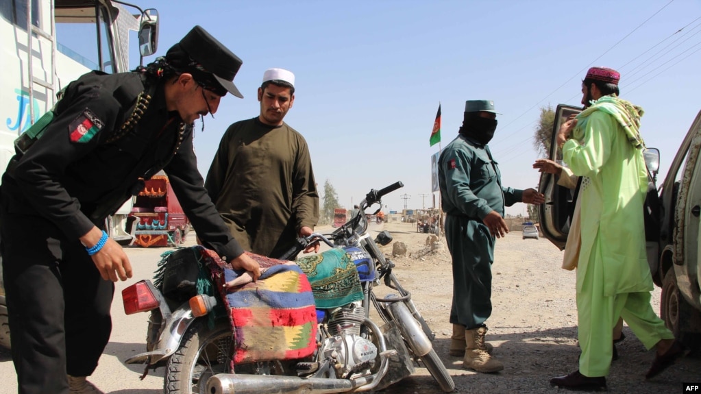 Afghan policemen search travelers at a checkpoint in Lashkar Gah in Helmand Province (file photo)