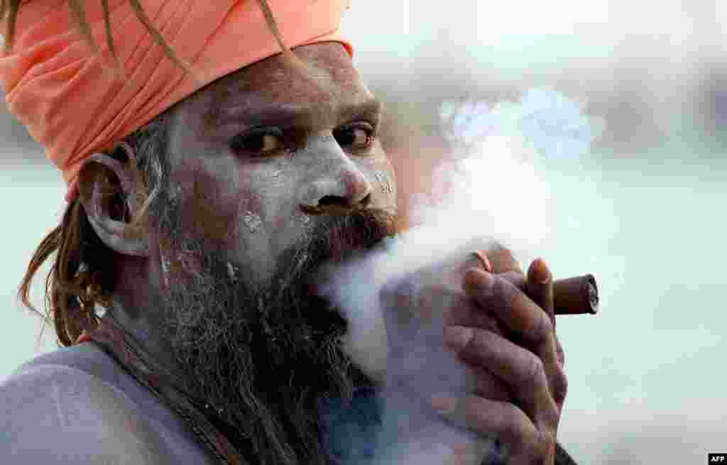 An Indian holy man smokes a &quot;chillum&quot; as he prepares for the upcoming Kumbh Mela festival in Allahabad, India. The Hindu festival is the largest gathering of people for a religious purpose in the world. Tens of millions of people gather for the multiweek occasion. (AFP/Sanjay Kanojia)