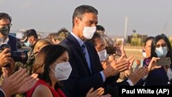 Pedro Sánchez spanyol miniszterelnök (középen) és Margarita Robles védelmi miniszter tapsol, amikor az Afganisztánból evakuált utolsó menekültek kiszállnak a repülőgépből a madridi Torrejón katonai bázison 2021. augusztus 27-én