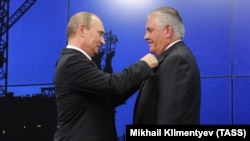 Then-ExxonMobil chief Rex Tillerson receives a state friendship award from Russian President Vladimir Putin in St. Petersburg in 2013.