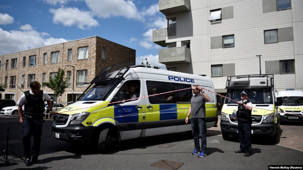 Officers and vehicles stand outside a block of flats that was raided by police in Barking, east London, following a deadly attack in the city that left seven people dead.