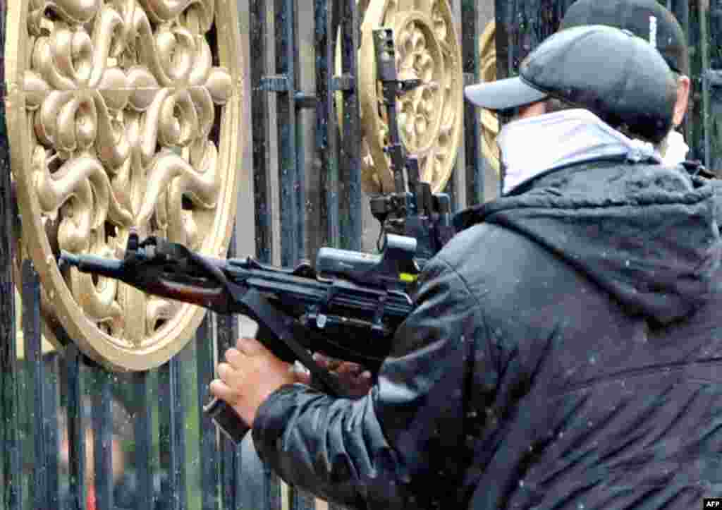 A Kyrgyz opposition supporter fires an automatic weapon near the main government building.