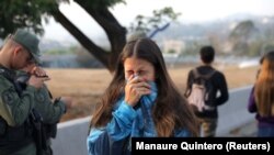 A woman reacts to tear gas near the <strong><a href="https://www.google.com/maps/place/Aeropuerto+Francisco+de+Miranda/@10.4880756,-66.8477082,17z/data=!3m1!4b1!4m5!3m4!1s0x8c2a584e28c2f8dd:0x91f417761b716b1c!8m2!3d10.4880756!4d-66.8455195" target="_blank">Generalisimo Francisco de Miranda Air Base</a></strong> in eastern Caracas. 
