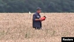 Відеокадр: працівник ДСНС на місці катастрофи несе, вочевидь, одну з «чорних скриньок», 18 липня 2014 року