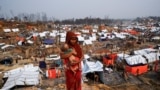 BANGLADESH-ROHINGYA/FIRE/ A Rohingya refugee woman carries her child as she looks on in a refugee camp after a massive fire broke out two days ago in Cox's Bazar, Bangladesh, March 24, 2021. 