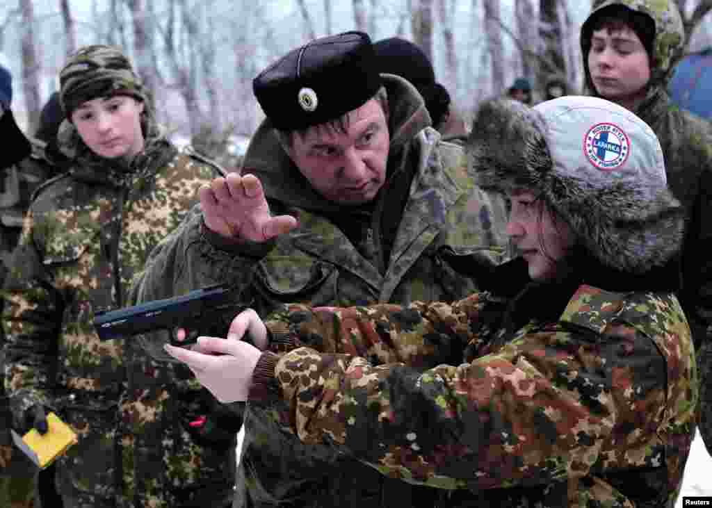 An instructor guides a student from the General Yermolov Cadet School as she aims during a field exercise outside the southern city of Stavropol, Russia. (Reuters/Eduard Korniyenko)