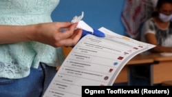 Një qytetare mban fletën e votimit në një vendvotim në Maqedoninë e Veriut - Fotografi ilustruese nga arkivi. 