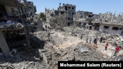 Палестинцы собираются на месте разрушенных домов после израильских воздушных и артиллерийских ударов. 14 мая 2021 года.