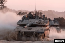 An Israeli soldier gestures on top of a tank, near the Israel-Gaza border in August.