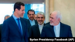 Syrian President Bashar al-Assad (left) speaks with Iranian Foreign Minister Mohammad Javad Zarif in Damascus on April 16. 