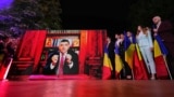 George Simion (AUR) transmite mesajul victoriei în primul tur al alegerilor prezidențiale, de la un birou având în fundal o bibliotecă cu icoane. Nu a venit în fața jurnaliștilor și a colegilor. Cuvintele sale au fost înregistrate și difuzate la ora exit-poll-urilor. 