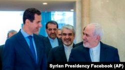 Syrian President Bashar Assad, left, speaks with Iranian Foreign Minister Mohammad Javad Zarif, right, in Damascus, April 16, 2019