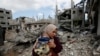 Palesztin nő gyerekével Gázában 2021. május 23-án a romoknál, amelyek a házukból maradtak a Hamász és Izrael közötti rakétaháború közepette