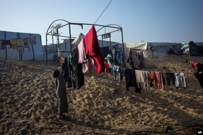 Majida Abu Jarad, e cila u zhvendos nga bombardimet izraelite të Rripit të Gazës, mbledh rrobat në një kamp të improvizuar në zonën Muasi. 1 janar 2024.