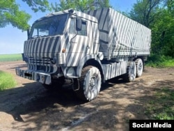 A Russian logistics vehicle painted in black and white stripes at an unspecified location