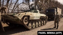 Украинский военнослужащий проходит рядом с танком российской армии, 29 марта 2022 года