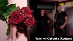 Ukrainian police officers stand guard as flowers are placed near the entrance to the house where Russian journalist Arkady Babchenko was shot and mortally wounded in Kyiv on May 29. 