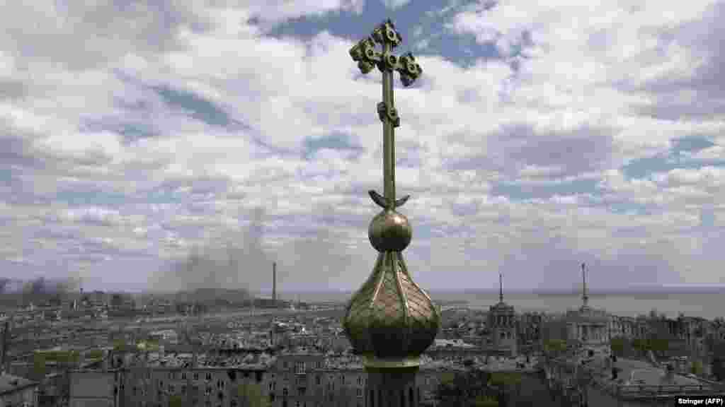 Во позадина на тековното руско гранатирање на челичарницата Азовстал на 10 мај, се гледа крст од црква.