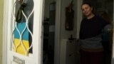 Anastasia Chukovskaya opening the door with Ukrainian flag on it