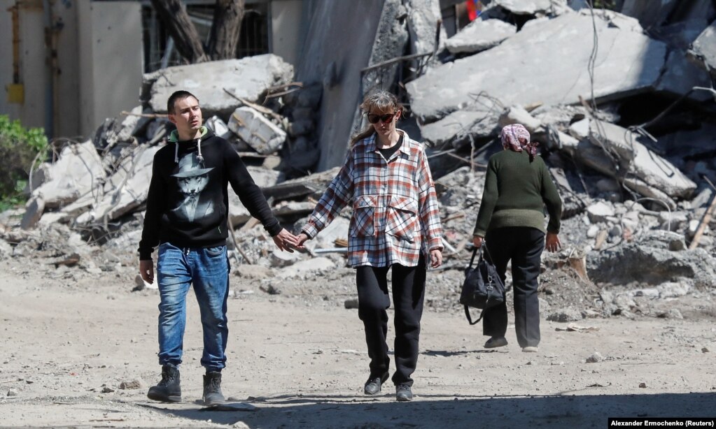 Një çift duke ecur dorë për dore, nëpër një zonë të shkatërruar banimi, më 12 maj.