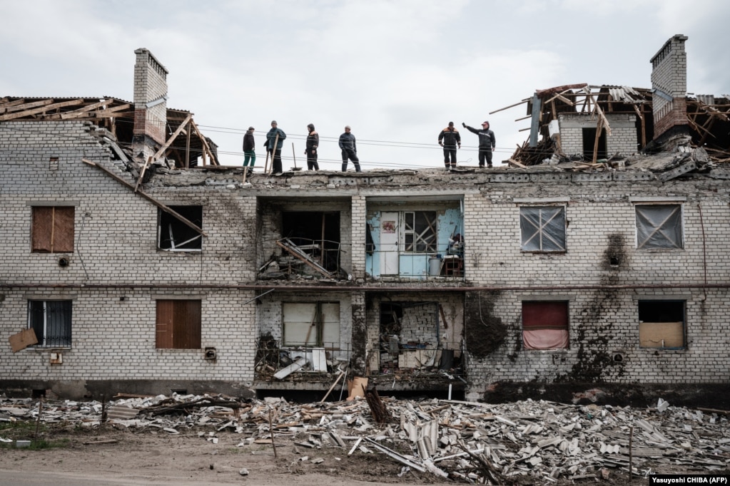 Punëtorët duke pastruar në kulmin e një ndërtese pothuajse të shkatërruar nga bombardimet një muaj më parë në Çerkaske, në Ukrainën lindore.