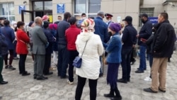 Люди стоят перед зданием почты в Кызылорде, чтобы получить социальную помощь в размере 42 500 тенге.