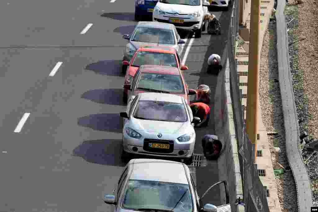 Israelis lay on the ground and take cover near their cars on the central highway while sirens sound over the city of Tel Aviv amid rocket attacks on July 9. (epa)