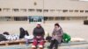 Жительницы Айболган Базарбаева и Амангуль Жаппасова (слева), объявившие голодовку, сидят на импровизированном лежаке перед зданием акимата Жанаозена. 31 марта 2022 года