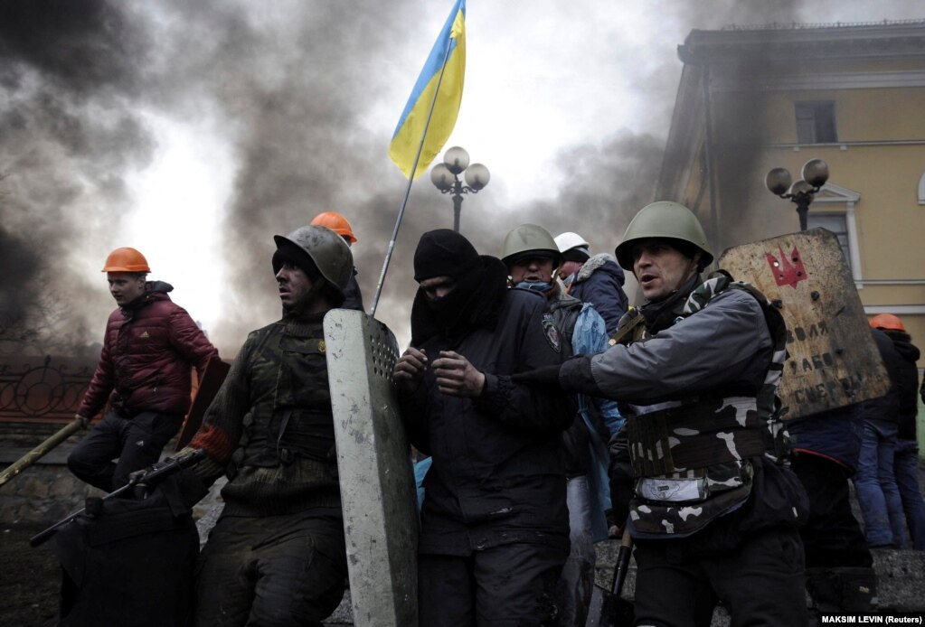 Protestuesit antiqeveritarë duke larguar një polic kundër trazirave nga Sheshi i Pavarësisë në Kiev, më 20 shkurt 2014.